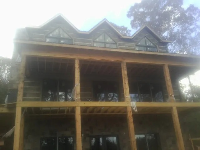 Dormers and porch framing on a large log home under construction — Roof Coating work by our crew in East Hampton