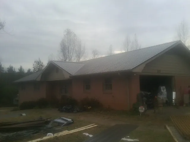 Gray metal roof on a stucco house with an attached garage in East Hampton