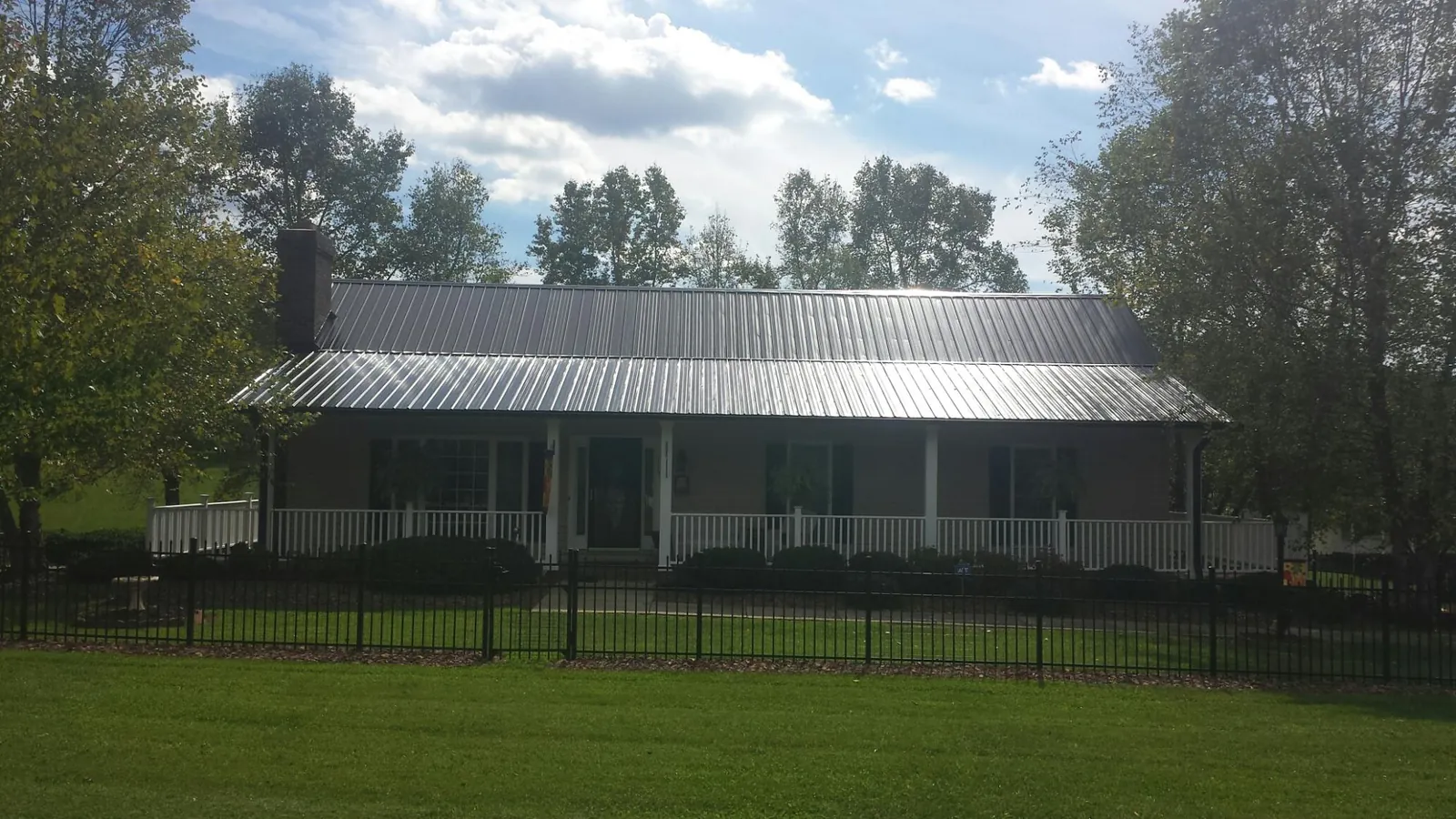 Gray metal roof on a brick ranch with a full width front porch — Gutter Guard Installation work by our crew in East Hampton