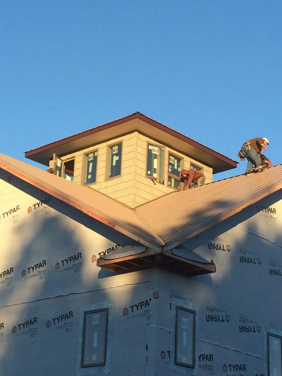Roofers working around a rooftop cupola on a new metal roof at sunset — Roof Waterproofing in East Hampton by Roofing Brothers